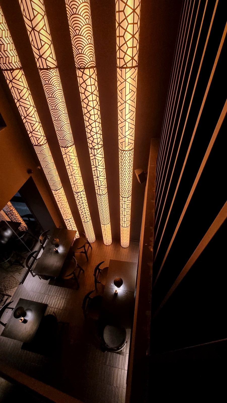 Looking down past the patterned columns of amber light to the tables of the Koyasan dining room.