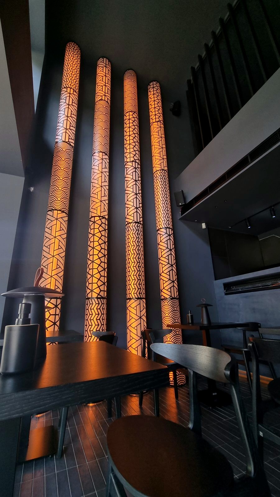 Small lamps on dark timber tables in front of glowing patterned columns at Koyasan.