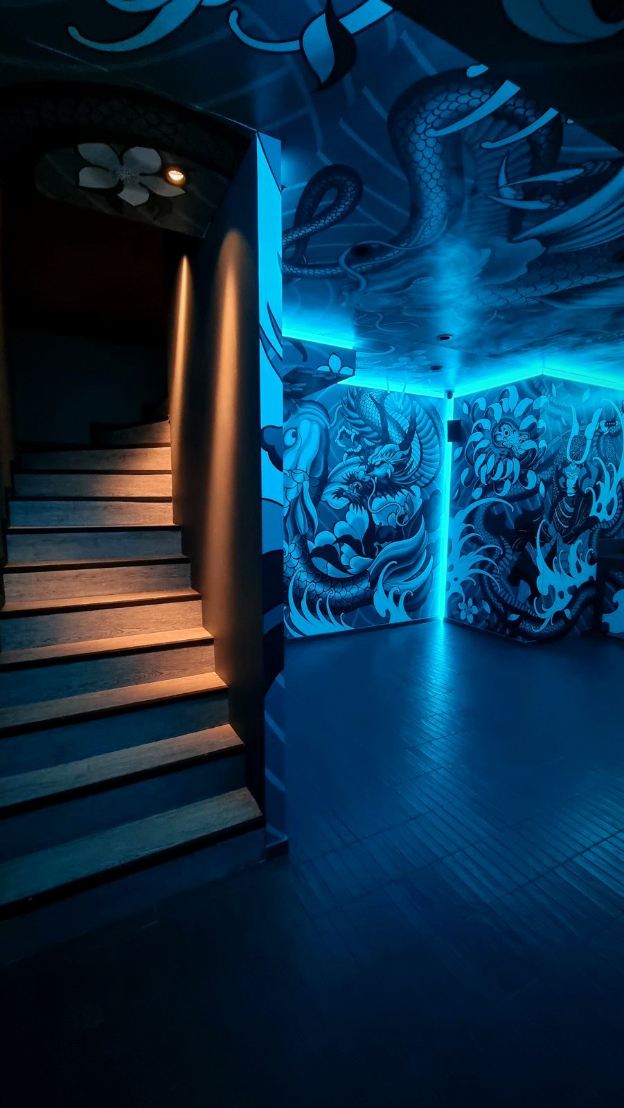 A stair beside mural covered walls washed in blue light at Koyasan.